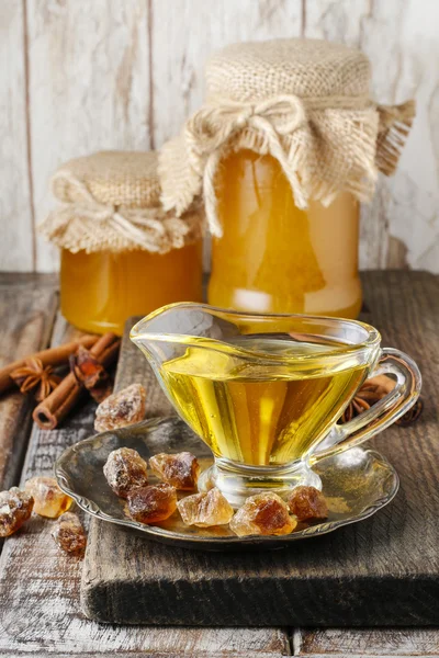 Jars and glass jug of honey on wooden table