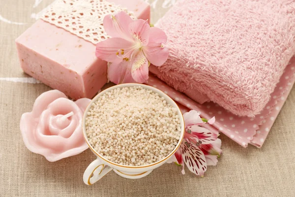 Bowl of sea salt, bar of soap, towels and alstroemeria flower
