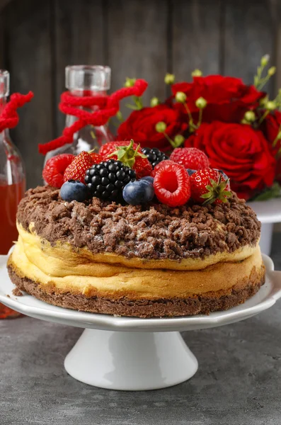 Cheesecake with chocolate topping decorated with summer fruits