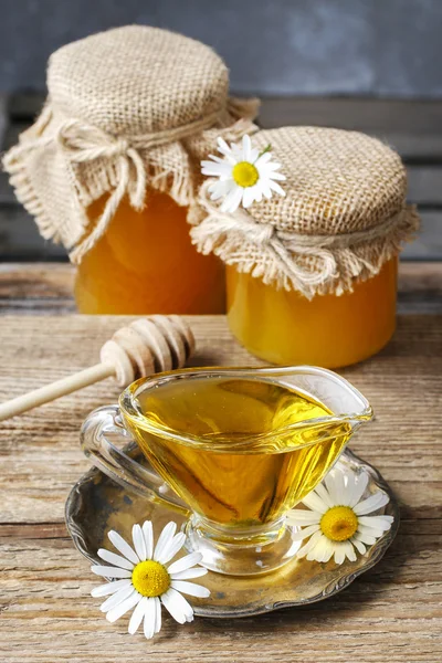 Jars and glass jug of honey on wooden table