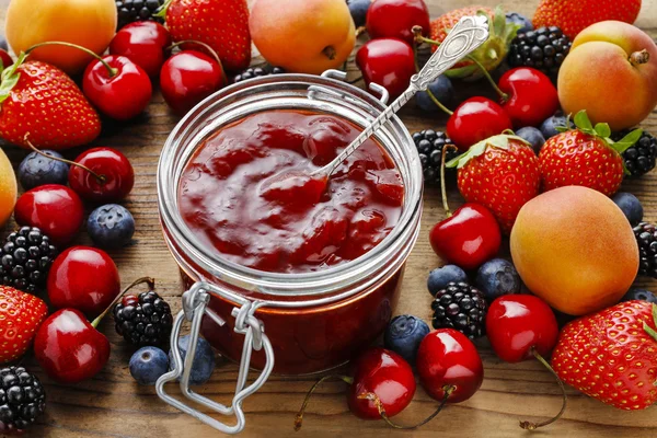 Jar of strawberry jams among summer and autumn fruits