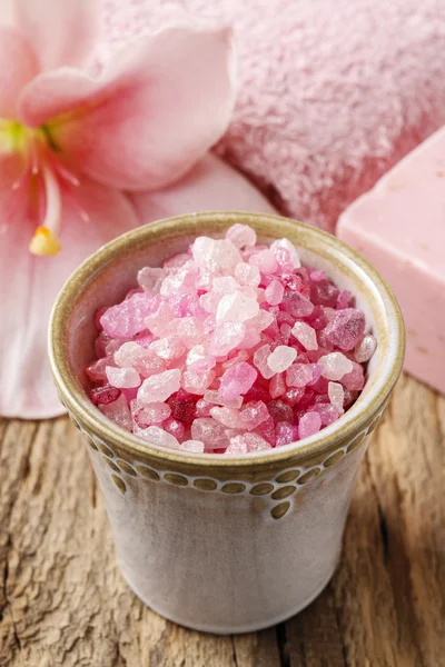 Bowl of pink sea salt and lily flower in the background