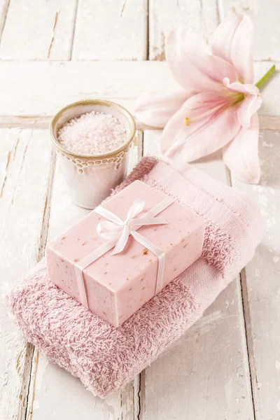 Bar of soap, bowl of sea salt, pink towel and lily flower