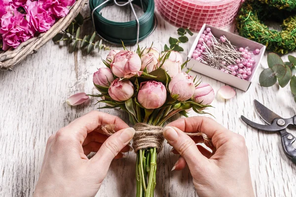 Woman making bouquet of pink roses.