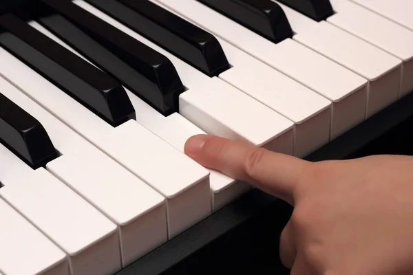 Child finger pressing white piano key