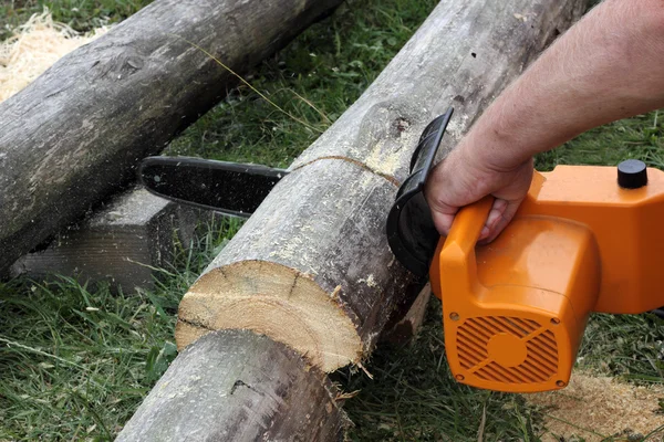 Worker cuts a beam by electric chain saw