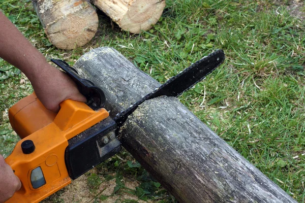 Worker cuts a beam by electric chain saw