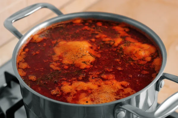 A pan of borsch cooking on a gas-stove