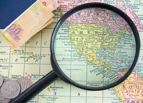 Magnifier and passport, money on world map background