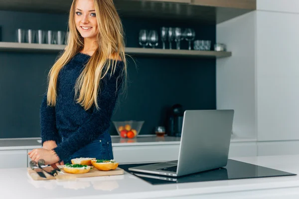 Young girl making sandwiches in the kitchen. Laptop on the kitch