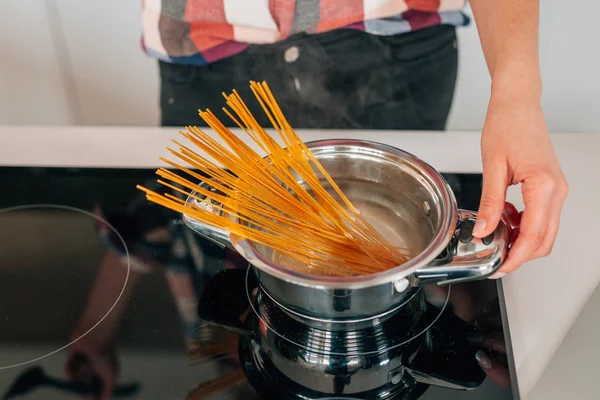 Girl is preparing spaghetti. She is boiling pasta. Close up