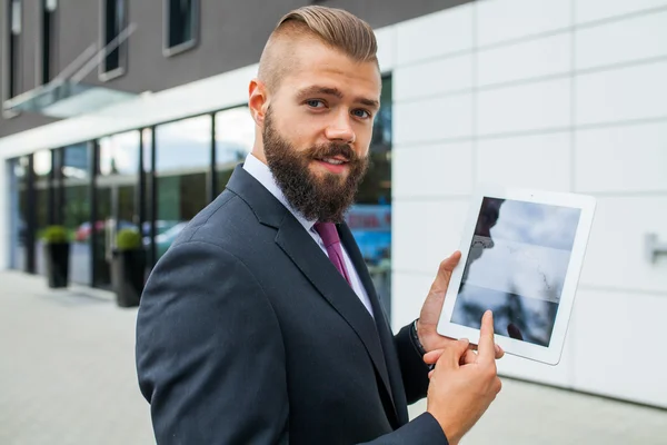 Young bearded businessman showing charts on tablet pc. Outdoor p