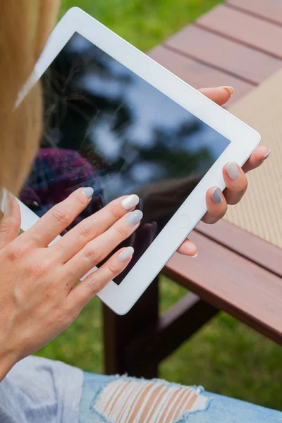 Woman sitting in park and using tablet pc