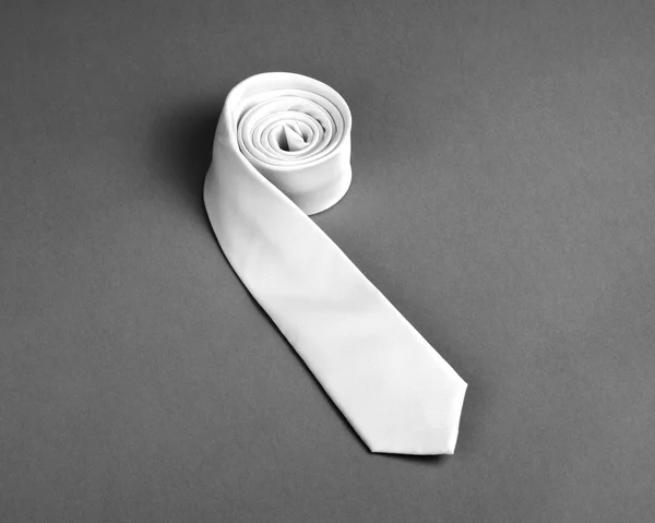 Beige necktie on gray background, roll of necktie on gray