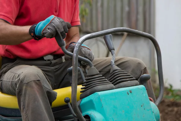 Man operating the gearshift of a mini digger