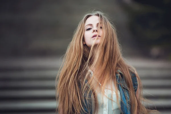 Beautiful girl with long blond hair blowing by wind. Toned image