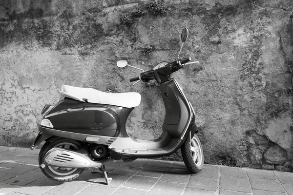 One motor scooter closeup against a stone wall
