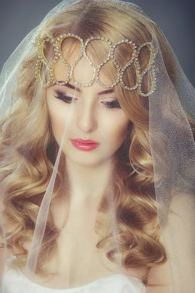 Beautiful young bride with blond hair under a veil