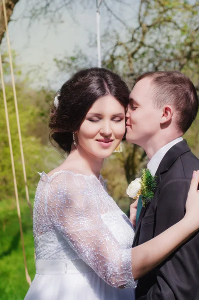 Young bride and groom in the park. Groom and bride in a white dress in the spring garden