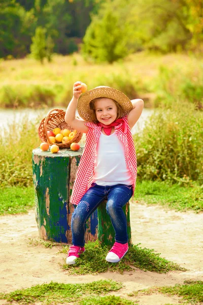 Little girl in jeans and a shirt near a river in autumn