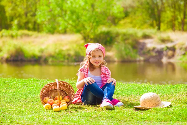 Little girl in jeans and a shirt near a river in autumn