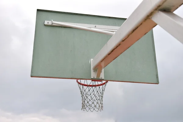 Behind of basketball board under cloudy sky in a school yard. Co