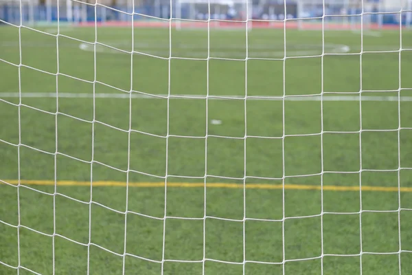 Close up detail of a soccer net against green grass on a cloudy