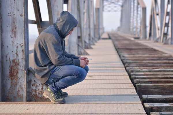 Thinker teenager in depression sitting down on the bridge at the