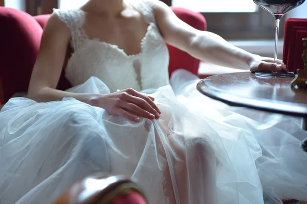 Beautiful young bride in a white dress sits at a wooden table wi