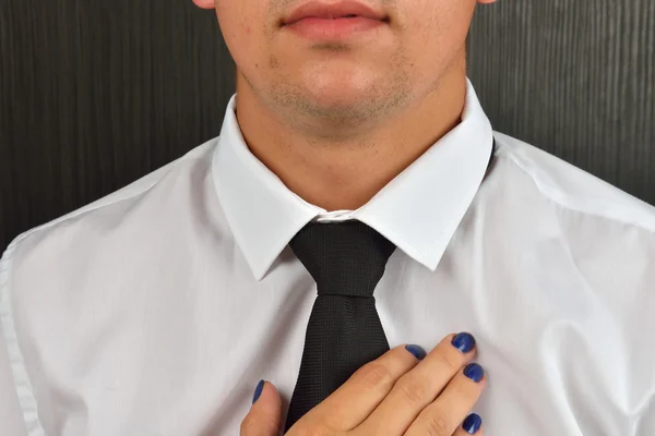 Woman\'s hands adjusting black tie and the neck of the shirt. Wif