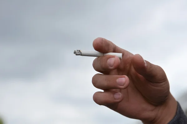 Man holding cigarette in his hand closeup outdoor. Cropped shot