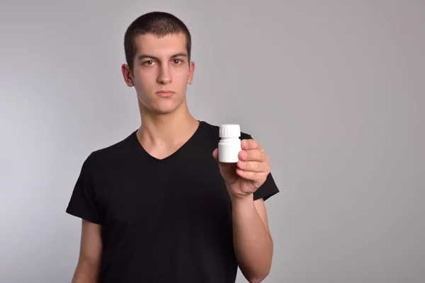 Young man holding a box of pills in his hand and shows the drugs directly into the camera