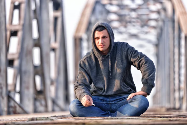 Thinker teenager in depression sitting down on the bridge at the