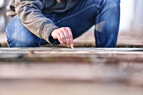 Hand of a young man extinguishing cigarette on a old bridge. Con