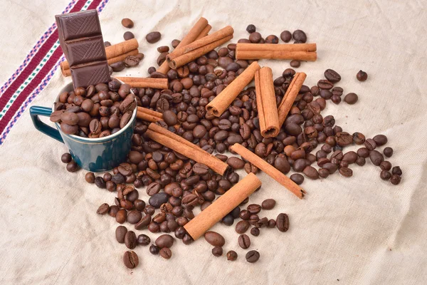 Cup of coffee with cinnamon sticks, bar of chocolate on vintage