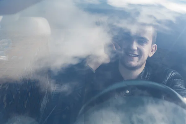 Young man driving and speaking on the phone