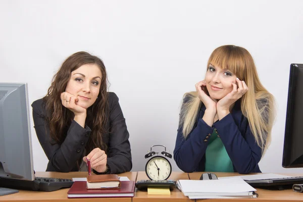 Two girls in the office waiting for the end of working hours on the clock