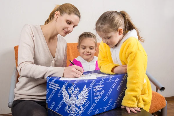 Volgograd, Russia - February 24, 2016: Mother and two daughters fill the form to send parcels to Russia post