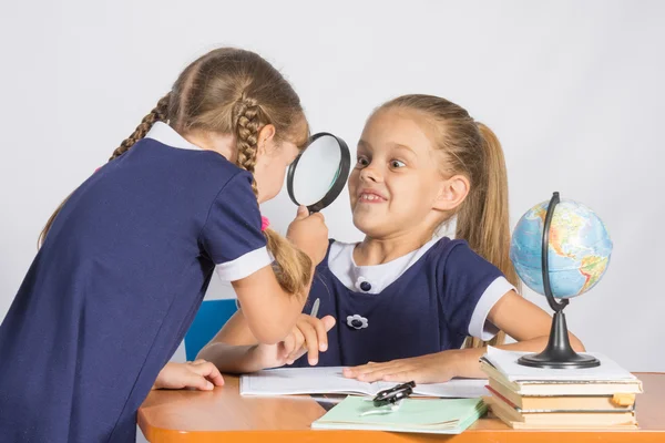 Girl looking at the other girl with a magnifying glass on a geography lesson