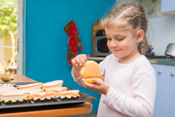 The child is prepared for the feast of Easter, laying on a baking tins Easter cupcakes