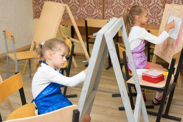 Two girls at a drawing lesson paint on easels