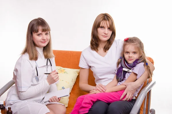 Sick girl measures the temperature of sitting on lap mother and doctor writes a complaint