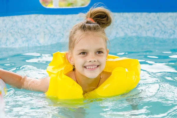 Cheerful girl swimming in pool swimming vest