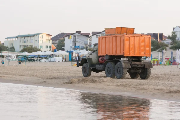 Garbage truck driving on the beach the sea coast in the early morning