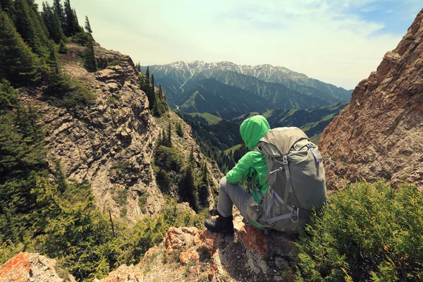 Backpacker sitting on mountain peak