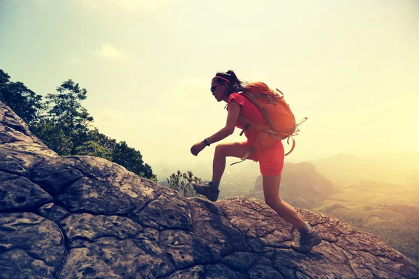 Asian woman hiker climbing rock