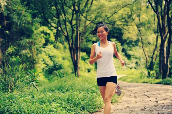 Young fitness woman running at forest trail