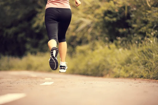 Young fitness woman legs running at forest trail