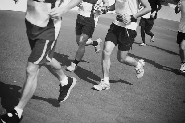 Marathon athletes legs running on city road