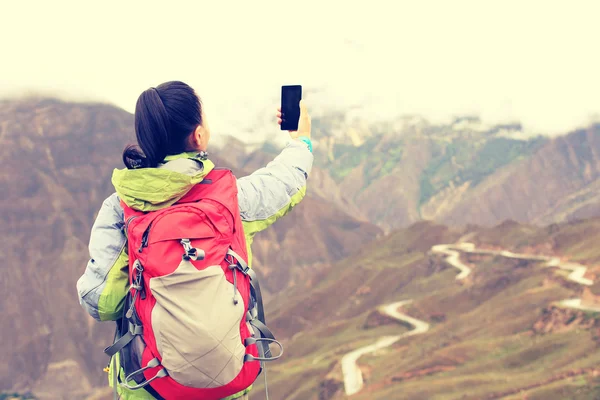 Hiker on mountain top with smartphone